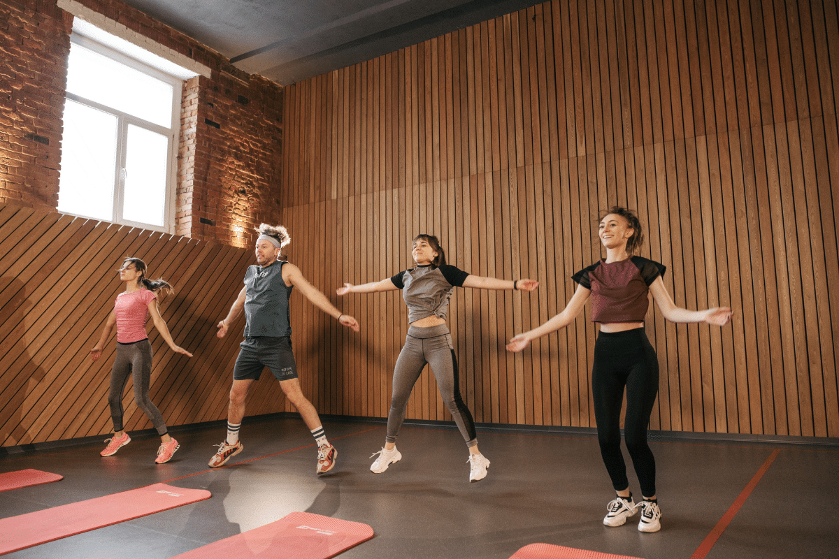 Leute machen Hampelmänner im Fitnessstudio, was auch im Home Office hilft gesund zu bleiben.